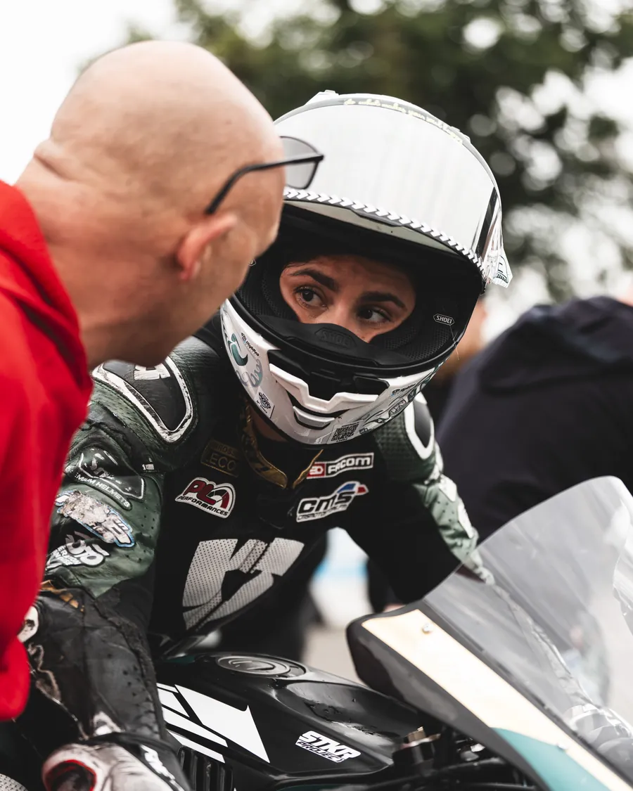 Philippe Ciminera penché vers un pilote casqué sur sa moto, juste avant le départ